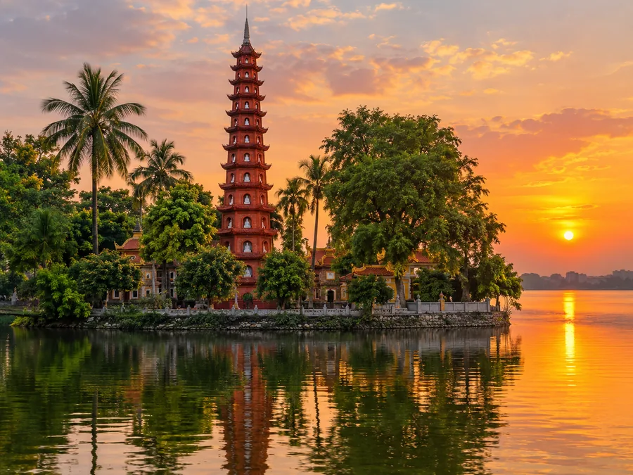 Bảo tháp gạch đỏ cao của chùa Trấn Quốc in bóng xuống Hồ Tây lúc hoàng hôn